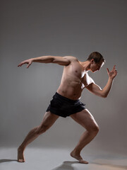 Muscular man in an artistic pose, portrait on a gray background. An athlete guy with spectacular muscles poses like an antique hero - 524886768