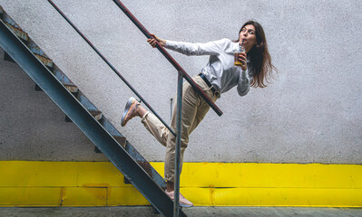 Business young woman near the stairs with a cup of coffee.