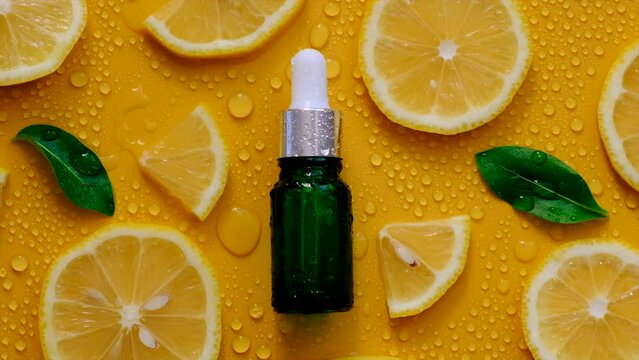 Lemon essential oil on a yellow background with water drops. Selective focus.