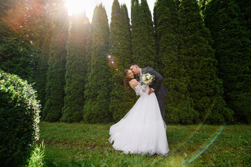 Handsome groom man in gray suit kissing and hugging pretty bride with curly hair in wedding puffy...