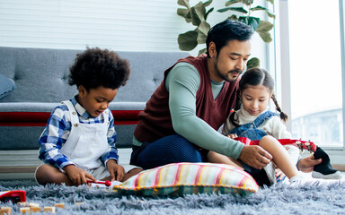 Single handsome father taking care with love to adopted children who are little diverse Caucasian, African girl and boy, sitting on floor in living room at home. Lifestyle, family, kids Concept.