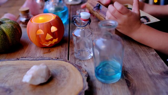 child makes magic with wooden box, casket, out of focus, girl in witch hat at school of wizards, Halloween holiday, pumpkin jack with candle, magical attributes, development of imagination