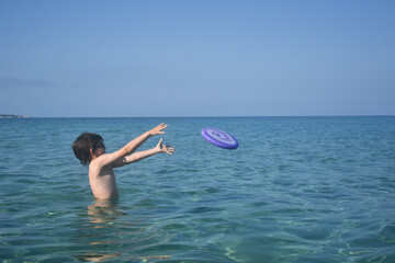 Happy boy play with frisbee in the sea. Summer vacation concept  child play in the water