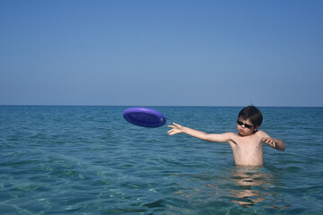 Happy boy play with frisbee in the sea. Summer vacation concept  child play in the water