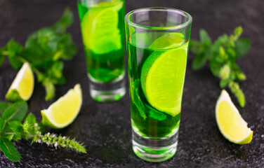 Mint liqueur with limes on a black background.Close-up.
