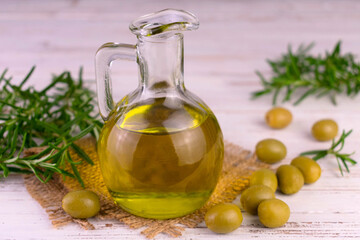Olive oil in a glass carafe and fresh rosemary.
