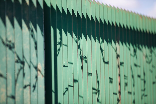Nahaufnahme eines grünen Zauns mit Stacheldraht - Abstrakt Seitlich Fotografiert mit Schattengebung