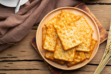 Dry thin crispy crackers in wooden plate on wood table.Top view
