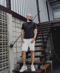 A young man in t-shirt and shorts on the stairs at city streets