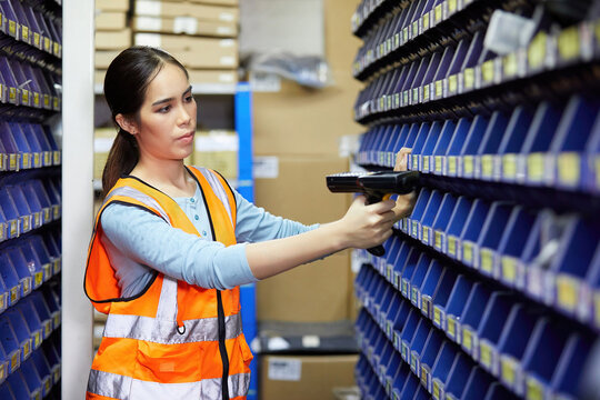 Factory Worker Using Laser Barcode Scanner And Looking Spare Parts Storage Cabinet