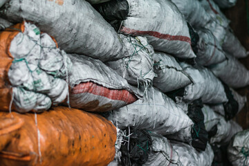 Fototapeta na wymiar white and orange sacks filled with material and products inside a warehouse. sacks filled with charcoal ready to be processed and sold in the colombian market. sale of material for food processing.