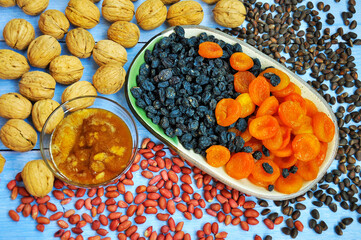 Mix dried fruits on a plate and different nuts on the table. Food background.