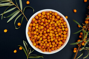 Fresh sea buckthorn on a twig and in a cup. View from above.