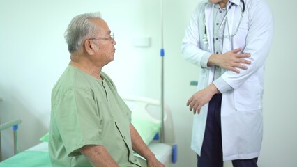 Elder Asian man sitting on the bed and talking to doctor about his physical injuries at his knees.