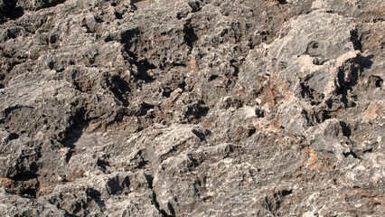 Texture of black rocks eroded by sea water