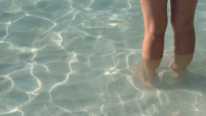 Woman's legs in crystal clear blue water