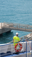 Worker of a big ship from the back with yellow clothes and safety case