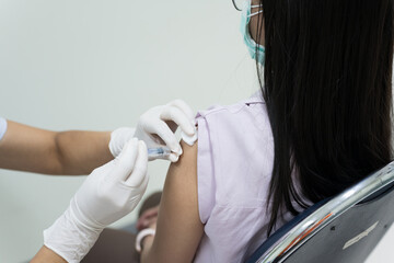 Close up doctor's hand injecting for vaccination in the shoulder woman patient and wearing a face...