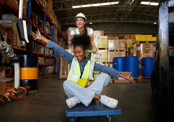 factory workers moving cart and having fun in the warehouse storage