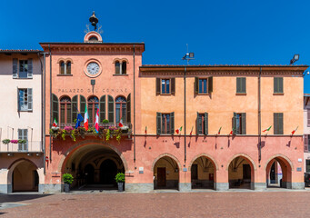 Naklejka premium Alba, Langhe, Piedmont, Italy - August 16, 2022: the town hall building of Alba with the flowered balconies and the Italian national flag, the flag of the Piedmont region and the European one