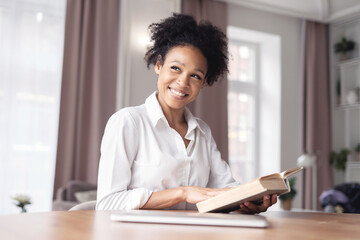 A woman online learning at home reading a book doing a task