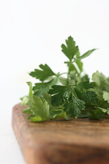 bundle of greens on wooden cutting board isolated on white background