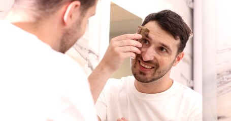 Fototapeta premium portrait of a caucasian male person combing his eyebrow.