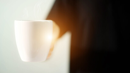 Man holding a white coffee cup and smoke from glass.
