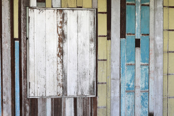 White grunge wooden window on multicolored grunge wooden wall.