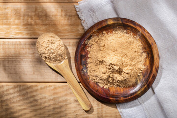 Maca powder, in wooden bowl on the table, nutritional substance from Peru