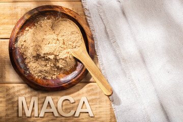 Maca powder, in wooden bowl on the table, nutritional substance from Peru