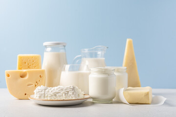 Variety of dairy products on blue background. Jug of milk, cheese, butter, yogurt or sour cream, cottage cheese. Farm dairy products concept