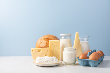 Variety of dairy products on blue background. Jug of milk, cheese, butter, yogurt or sour cream,...