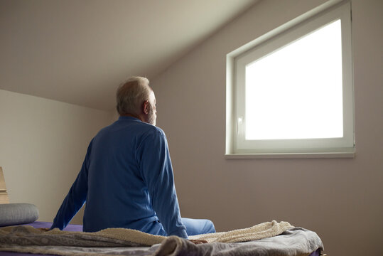 Senior Man Sitting In Bed After Waking Up In The Morning