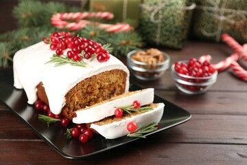 Traditional classic Christmas cake decorated with cranberries and rosemary on wooden table