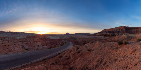 Fototapeta na wymiar Scenic Road in Red Rock Mountains in the Desert at Colorful Sunrise. Spring Season. Goblin Valley State Park. Utah, United States. Nature Background Panorama
