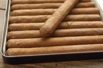 Many expensive cigars in box on wooden table, closeup