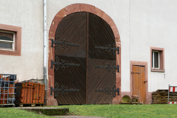 Ein großes Tor zum Ein- und Ausfahren mit Eichentüren und alten Scharnieren
