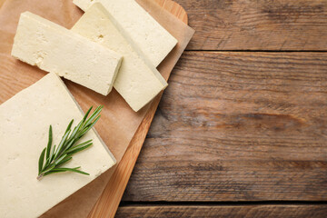 Delicious tofu with rosemary on wooden table, top view. Space for text