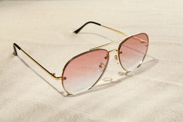 New stylish sunglasses on sand. Fashionable accessory