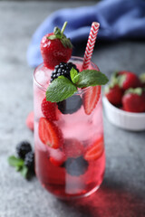 Delicious strawberry lemonade with soda water, mint and blackberries on grey table. Fresh summer cocktail