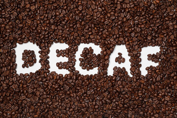 Obraz na płótnie Canvas Word Decaf in coffee beans on white background, top view