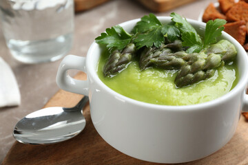 Delicious asparagus soup served on table, closeup