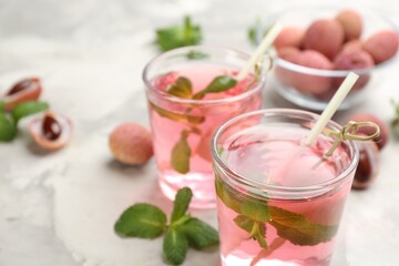 Lychee cocktail with mint and fresh fruits on grey marble table, closeup