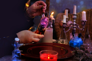 female witch, alchemist holds bottle with elixir of life in her hands, conjures in dark room, magic...