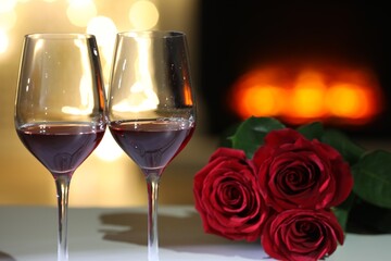 Glasses of wine and flowers on table against blurred lights. Romantic dinner