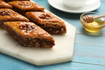 Delicious sweet baklava with walnuts on turquoise wooden table, closeup