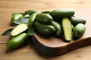 Fresh seedless avocados with green leaves on wooden table, closeup