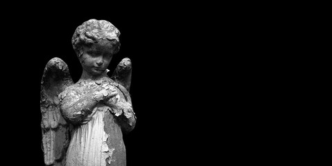 Fototapeta na wymiar Angel. A very ancient statue on black background. Copy space.