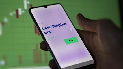 An investor's analyzing the low-sulphur gas etf fund on screen. A phone shows the ETF's prices low sulphur gas fund to invest